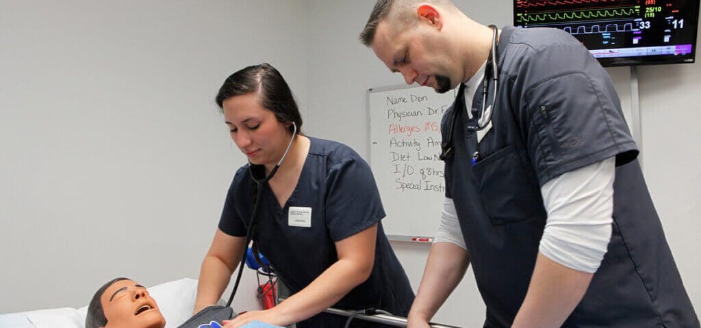 photo of Practical Nursing students in the lab working on simulator
